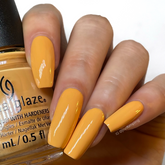 A woman's hand showing a glimpse of Tangerine Heat color nail polish in her nails while holding a nail lacquer bottle